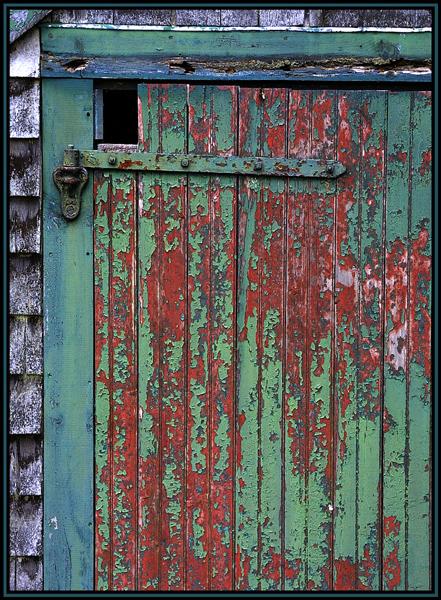 A door on an old shed. Peeling green paint reveals the older red paint. Part of Maudsley State Park in Newburyport, Massachusetts (US).