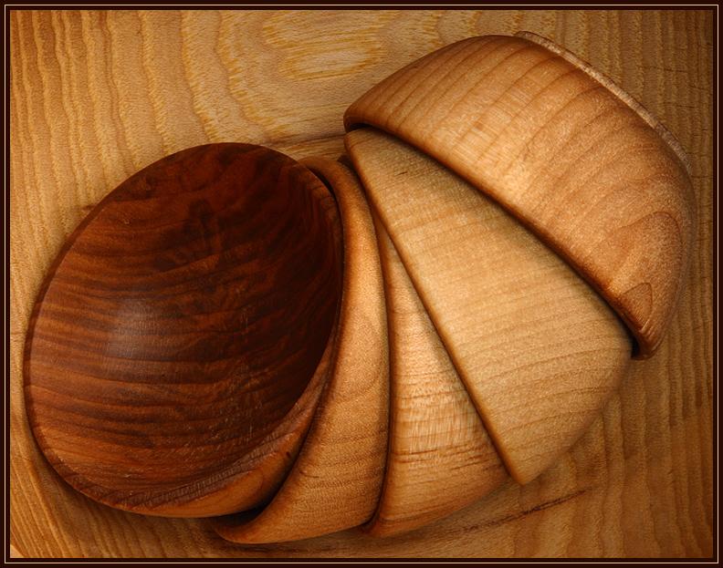 A set of small wooden bowls nested together and placed in a larger bowl.