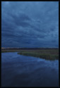 Dark, stormy clouds reflected in the water of the Newbury salt marsh (Newbury, Massachusetts US).